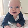 Ernest a rejoint le concours — aidez-le/la à gagner de superbes lots ! baby, infant, smiling, blue_eyes, face, hands, clothing, cushion, pattern, indoor, cute, portrait, child, young, happy, lying_down, onesie, navy_shirt, skin, head