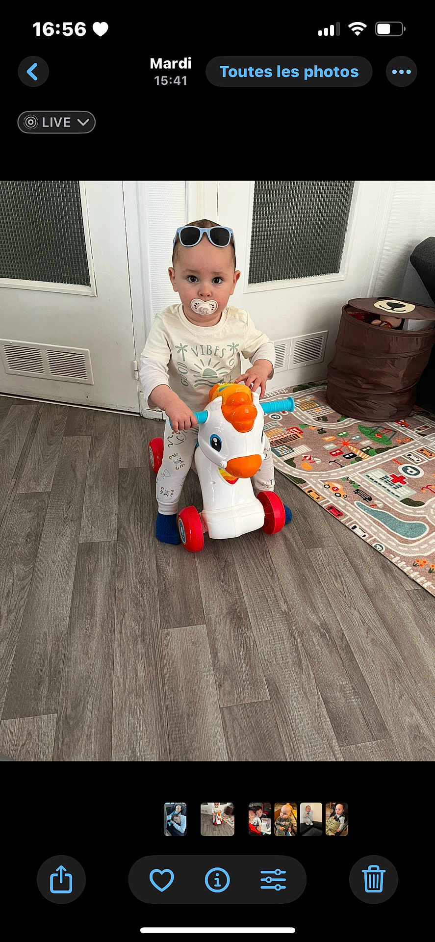 Mylan a rejoint le concours — aidez-le/la à gagner de superbes lots ! toddler, child, toy, indoor, pacifier, sunglasses, floor, play_mat, storage_basket, white_door, wooden_floor, clothing, person, baby, face, sitting, cute, room, plastic_toy, expression
