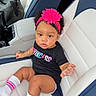 baby, black_shirt, bow, car, car_seat, child, curly_hair, cute, fashion, headband, indoors, infant, leather_seat, pink_flower, portrait, sitting, smiling, striped_socks, vehicle, white_socks