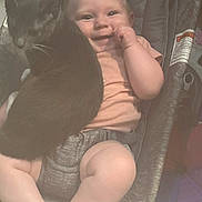 Ember joined the competition — help win amazing prizes! baby, cat, smile, infant, baby_carrier, cushion, indoor, pet, black_cat, white_paws, cute, happy, child, legs, hand, clothing, seat, face, comfort, domestic_animal