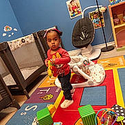 Heaven joined the competition — help win amazing prizes! child, toddler, standing, playroom, toys, colorful, activity_mat, baby_gear, high_chair, playpen, floor, indoors, portrait, face, clothing, red_shirt, black_pants, shoes, curious, children_furniture