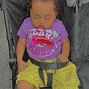 Arrianna is registered to the contest to win money with this photo: baby, buckle, calm, child, clothing, curly_hair, daylight, face, harness, infant, nap, outdoor, pavement, photography, portrait, purple_shirt, seated, sleeping, stroller, yellow_shorts