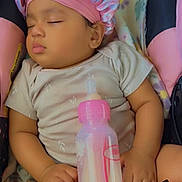 Arrianna is registered to the contest to win money with this photo: baby, sleeping, infant, child, portrait, pink_bonnet, hat, bottle, baby_bottle, blanket, cushion, seated, indoors, close_up, peaceful, nap, pink, clothing, sticker, princess