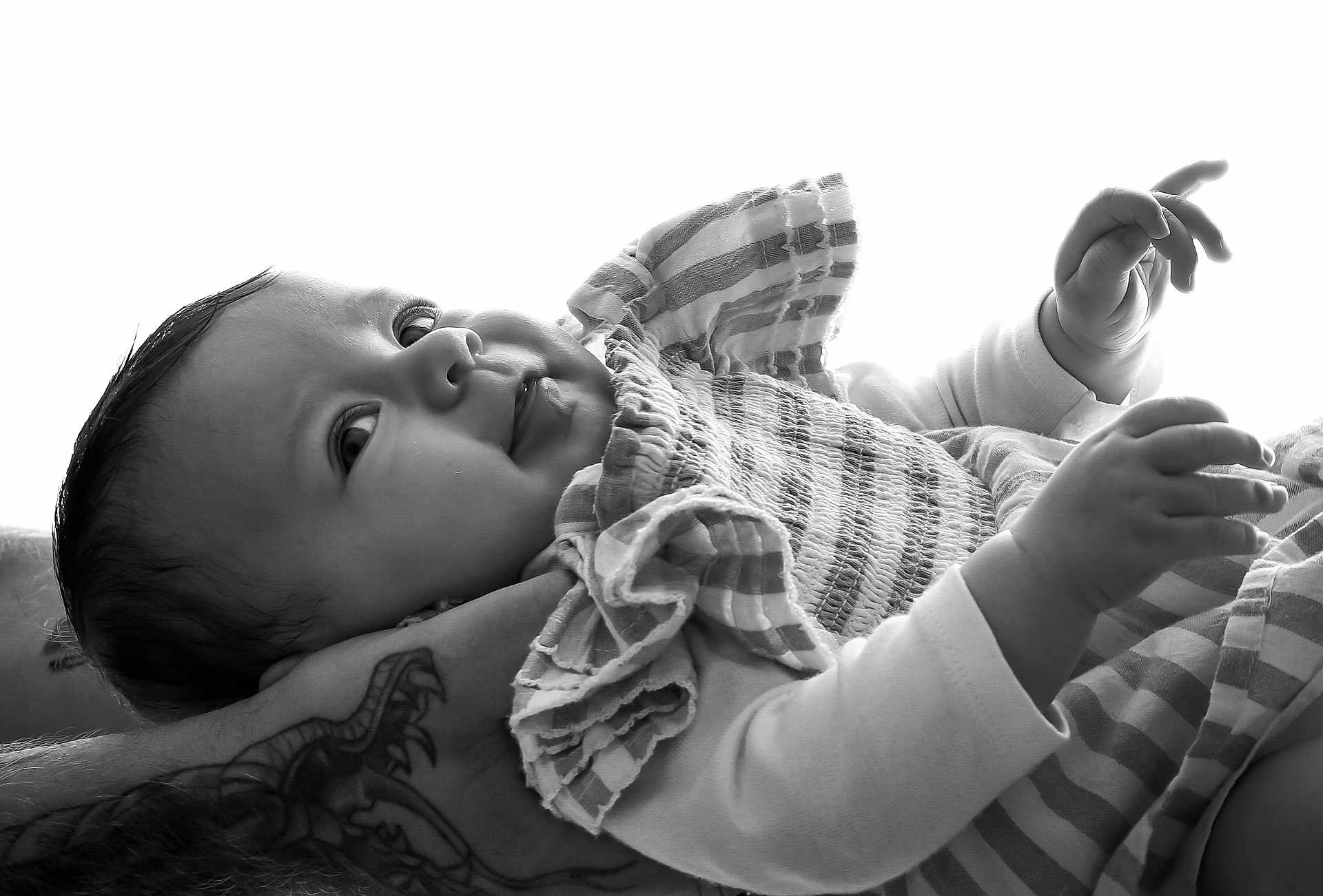 Aimée a rejoint le concours — aidez-le/la à gagner de superbes lots ! baby, infant, black_and_white, tattoo, arm, face, expression, clothing, striped, hand, portrait, curious, close_up, newborn, person, skin, cute, holding, soft_light, monochrome