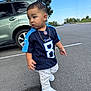 accessory, asphalt, blue_sky, car, casual_clothing, child, curious_expression, daytime, football_jersey, gold_chain, outdoor, parking_lot, person, sneakers, standing, suv, tennessee_titans, toddler, tree, white_jeans