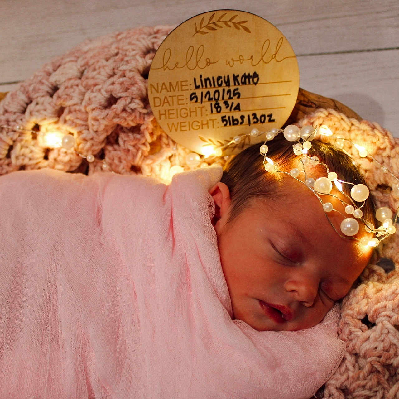 Linley Kate is registered to the contest to win money with this photo: baby, birth_details, closeup, cozy, crocheted_blanket, cute, fairy_lights, headpiece, indoors, infant, newborn, peaceful, pearls, pink_blanket, portrait, resting, sleeping, soft_lighting, wooden_sign, wrapped