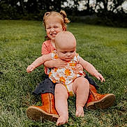 Oaklynne is registered to the contest to win money with this photo: child, baby, grass, outdoor, smiling, hugging, sitting, boots, dress, greenery, nature, playful, happy, toddler, person, summer, cute, siblings, portrait, fun