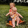 child, baby, grass, outdoor, smiling, hugging, sitting, boots, dress, greenery, nature, playful, happy, toddler, person, summer, cute, siblings, portrait, fun