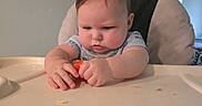 Hudson is registered to the contest to win money with this photo: baby, high_chair, food, table, infant, child, indoor, concentration, serious, clothing, face, hands, feeding, cute, young, person, expression, hair, skin, background