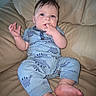 Hudson is registered to the contest to win money with this photo: baby, child, infant, pajamas, blue, dinosaur_pattern, couch, leather, furniture, hand, foot, sitting, curious, face, skin, hair, indoors, portrait, cute, expression