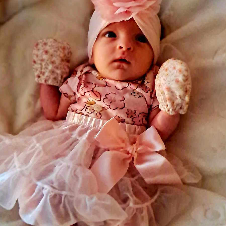 Issabell is registered to the contest to win money with this photo: adorable, baby, babywear, blanket, child, clothing, cute, dress, fabric, flower, headband, infant, laying, mittens, newborn, pink, portrait, sleepwear, small, soft
