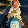 Yzak participe au concours pour gagner de l'argent avec cette photo : baby, child, toy_car, outdoor, smiling, happy, winter_clothing, mittens, hat, road, sunlight, playful, cute, vehicle, person, daytime, nature, trees, suburban, fun
