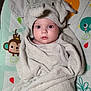 Xena joined the competition — help win amazing prizes! baby, towel, elephant_costume, wrapped, face, eyes, infant, child, cute, play_mat, monkey_print, bird_print, fabric, soft, indoors, portrait, smile, headwear, blanket, resting