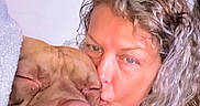 Atlas is registered to the contest to win money with this photo: woman, piglet, animal, pet, kiss, portrait, close_up, face, curly_hair, blanket, cozy, indoor, home, cuddling, pink, wrinkles, snout, eyes, affection, selfie