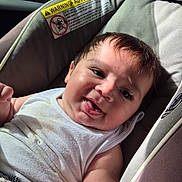 Levi joined the competition — help win amazing prizes! baby, infant, child, smiling, happy, portrait, car_seat, vehicle, indoors, outdoor_view, blanket, white_clothing, dark_hair, face, eyes, mouth, sitting, sunlight, road_trip, safety_label