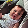 baby, infant, child, smiling, happy, portrait, car_seat, vehicle, indoors, outdoor_view, blanket, white_clothing, dark_hair, face, eyes, mouth, sitting, sunlight, road_trip, safety_label