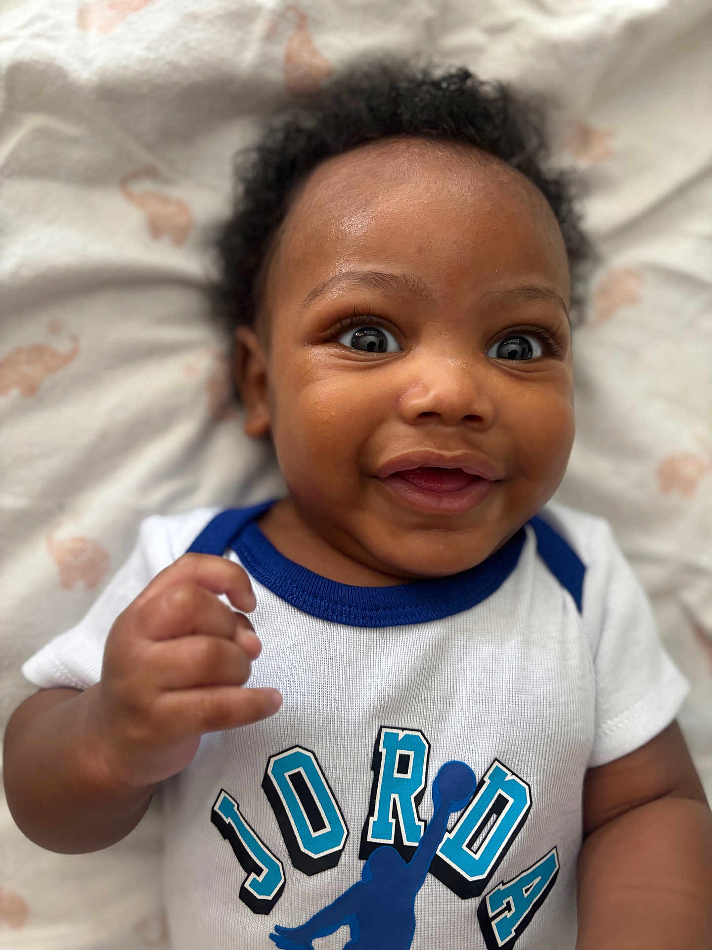 Giovanni joined the competition — help win amazing prizes! baby, smiling, happy, face, infant, clothing, tshirt, person, lying_down, cute, child, closeup, portrait, skin, hand, soft, blanket, animal_print, indoors, young