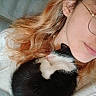 kitten, cat, woman, glasses, curly_hair, cozy, sleeping, black_and_white, pet, close_up, indoor, soft_light, warm, human_face, animal, cute, resting, comfort, snuggle, portrait