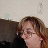 person, cat, glasses, couch, kiss, black_and_white_cat, indoor, wall_stickers, affection, cozy, casual_clothing, short_hair, light_brown_hair, relaxing, close_up, pet, home, comfort, friendship, love