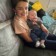 Aaron participe au concours pour gagner de l'argent avec cette photo : child, baby, smile, couch, cushion, window, indoor, family, holding, happy, person, clothing, sitting, cozy, home, casual, portrait, two_people, infant, relaxation