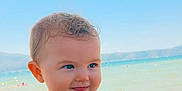 Leyna a rejoint le concours — aidez-le/la à gagner de superbes lots ! baby, child, blue_clothing, beach, sea, sky, water, sunlight, smile, person, portrait, summer, vacation, holding, cute, outdoor, happy, skin, hand, nature