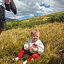 Leyna a rejoint le concours — aidez-le/la à gagner de superbes lots ! baby, child, outdoor, grass, hill, sky, clouds, sunlight, person, nature, curly_hair, white_sweatshirt, red_pants, socks, smile, greenery, shrub, adult, casual_clothing, landscape