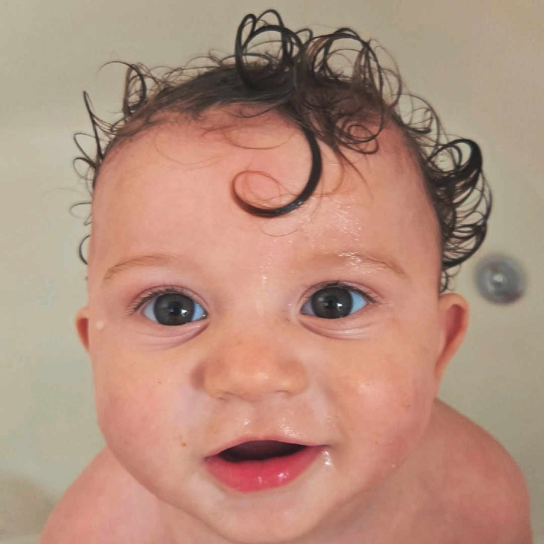 Elijah is registered to the contest to win money with this photo: baby, bath, bathtub, child, close_up, curly_hair, cute, eyes, face, hands, indoor, innocence, mouth, person, portrait, skin, smiling, water_droplets, wet_hair, young