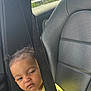 Namirah is registered to the contest to win money with this photo: toddler, child, car_seat, seatbelt, yellow_shirt, sneaky_look, leather_seat, car_interior, window, daylight, urban_background, hair_buns, sneakers, expression, person, sitting, clothing, seatbelt_strap, vehicle, portrait
