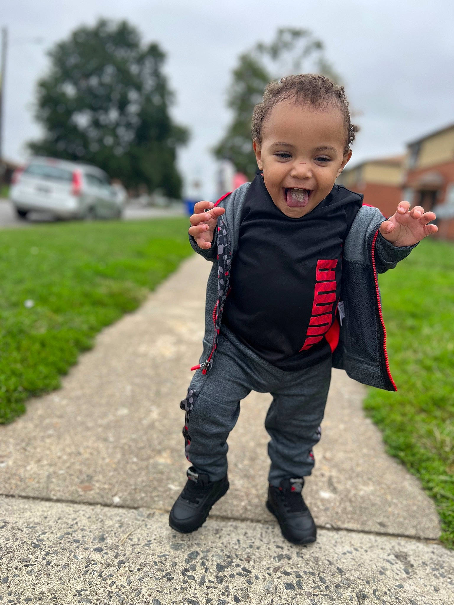 Kaiden is registered to the contest to win money with this photo: asphalt, baby, baby_toddler_clothing, boot, child, footwear, fun, gesture, grass, happy, jacket, leisure, people_in_nature, person, plant, recreation, sky, sleeve, sneakers, toddler