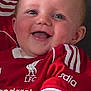 baby, child, smiling, red_jersey, liverpool_fc, football_shirt, happy, face, blue_eyes, arm, person, cute, infant, portrait, clothing, indoor, holding, skin, expression, sportswear