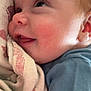 Atlas is registered to the contest to win money with this photo: baby, close_up, face, blanket, infant, blue_shirt, skin, cheeks, mouth, nose, eye, ear, soft_texture, cuddling, person, child, newborn, expression, young, comfort