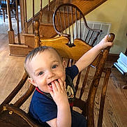 Merrick Gerstenmier is registered to the contest to win money with this photo: toddler, child, high_chair, wooden_chair, cereal, food, smile, happy, indoor, home, stairs, wood_floor, table, plate, person, face, hand, blue_shirt, cute, baby