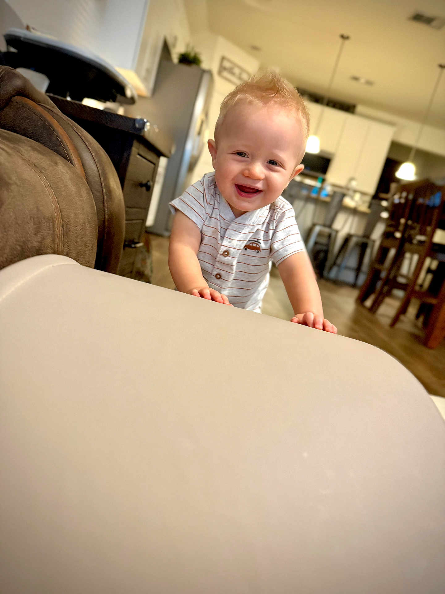 Lincoln is registered to the contest to win money with this photo: toddler, child, smiling, indoor, kitchen, furniture, table, light, happy, person, short_hair, blond, casual_clothing, wood_floor, cabinet, chair, modern, home, cute, portrait