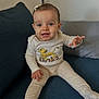 Amalya a rejoint le concours — aidez-le/la à gagner de superbes lots ! baby, child, smiling, blue_eyes, sitting, couch, clothing, onesie, hair_clip, indoor, cute, person, infant, happy, plush, portrait, light_skin, young_child, toy_character, simba