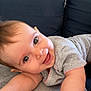 baby, smiling, face, eyes, arm, hand, blanket, couch, indoors, clothing, happy, infant, person, skin, cheerful, cute, baby_girl, baby_boy, lying_down, playful