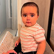 Charlotte a rejoint le concours — aidez-le/la à gagner de superbes lots ! baby, child, indoor, striped_shirt, black_pants, changing_pad, sitting, curious_expression, wide_eyes, short_hair, soft_lighting, neutral_wall, foot, hand, person, portrait, young_child, comfortable, patterned_surface, cozy