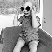 Cléa participe au concours pour gagner de l'argent avec cette photo : toddler, child, sunglasses, smile, indoor, happy, baby, clothing, shorts, topknot, hands, legs, cushion, monochrome, portrait, cute, joyful, fashion, playful, sitting