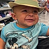 baby, blue_shirt, cartoon, child, close_up, fedora, happy, hat, indoor, infant, mickey_mouse, portrait, retail, seated, shelves, shoe_store, shoes, shopping, smiling, straw_hat