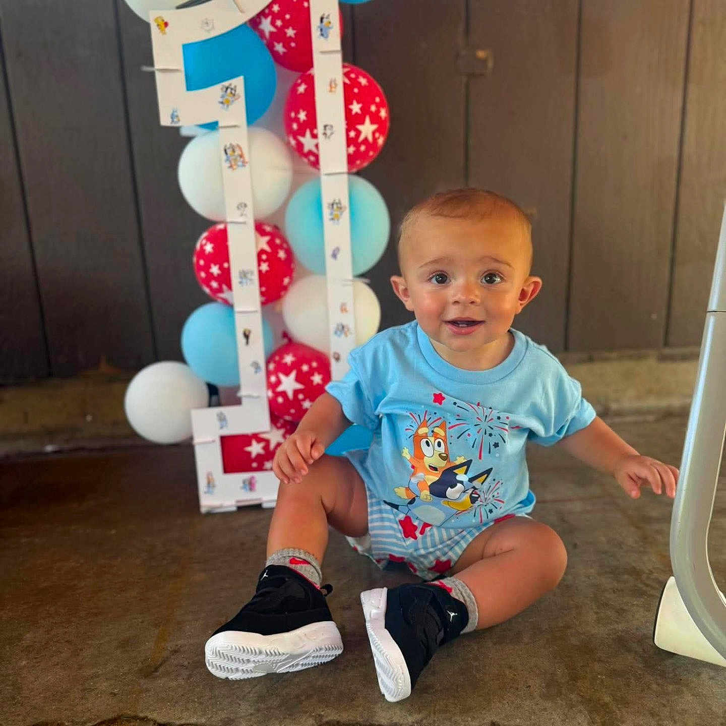 Joziyah joined the competition — help win amazing prizes! baby, backdrop, balloons, birthday, blue_shirt, celebration, child, decorations, floor, happy, indoor, infant, party, portrait, sitting, smiling, sneakers, star_pattern, striped_shorts, toy_graphic