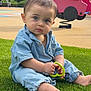 baby, child, grass, playground, toy, blue_outfit, barefoot, spring_rider, green_toy, outdoor, nature, curious, sitting, young_child, face, person, daylight, casual_clothing, park, play