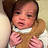 Kyan is registered to the contest to win money with this photo: awake, baby, bib, brown, child, close_up, clothing, cozy, eyes, face, hands, indoors, infant, looking_at_camera, newborn, photography, pillow, portrait, soft_lighting, white_sleeves