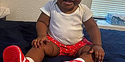 Jariya joined the competition — help win amazing prizes! baby, bed, blanket, cheeks, child, cuteness, footwear, hair_tie, happy, indoor, person, polka_dot, red_and_white, red_shorts, sitting, skin, smiling, sneakers, white_shirt, window_blinds