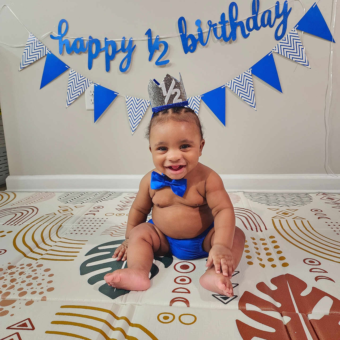 Kayde is registered to the contest to win money with this photo: accessories, baby, birthdaycake, cake, clothing, cream, crown, dessert, diaper, face, formalwear, hat, head, indoors, jewelry, person, photography, portrait, sitting, tie