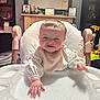 Brooke is registered to the contest to win money with this photo: baby, high_chair, infant, smiling, indoor, table, hand, face, person, clothing, bib, furniture, photograph, lamp, toy, living_room, portrait, child, cute, home