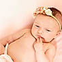 baby, infant, headband, flower, pink, blanket, skin, hand, face, portrait, cute, child, peaceful, lying_down, soft_light, indoors, newborn, expression, resting, young