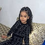 Widad participe au concours pour gagner de l'argent avec cette photo : child, girl, curly_hair, braids, black_dress, white_tights, sitting, couch, pillows, indoor, patterned_fabric, long_sleeves, fashion, portrait, young, pretty, relaxed, smiling, home, casual