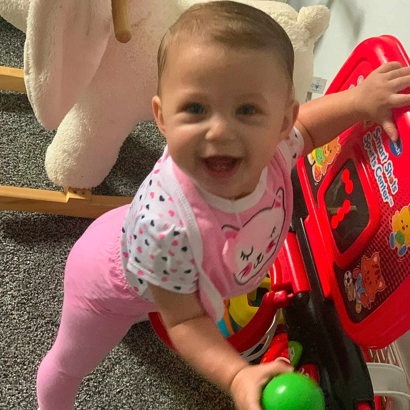 Kaylee joined the competition — help win amazing prizes! baby, babysock, ball, carpet, child, colorful, cute, face, furniture, happy, indoor, person, pink_clothing, play, playroom, rocking_animal, smiling, toddler, toy, young_child