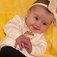 Caroline joined the competition — help win amazing prizes! baby, infant, child, smiling, portrait, lying_down, yellow_blanket, bow_headband, white_shirt, long_sleeves, black_pants, hands, face, eyes, indoor, closeup, happy, cute, textile, photograph