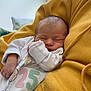 newborn, baby, sleeping, infant, yellow_hoodie, cozy, soft_light, indoor, person, closeup, peaceful, cute, child, resting, portrait, hand, face, clothing, window, pillow