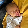 baby, newborn, sleeping, infant, person, hand, clothing, yellow_sweater, white_outfit, closeup, soft_lighting, portrait, indoor, resting, peaceful, human, skin, face, head, cozy